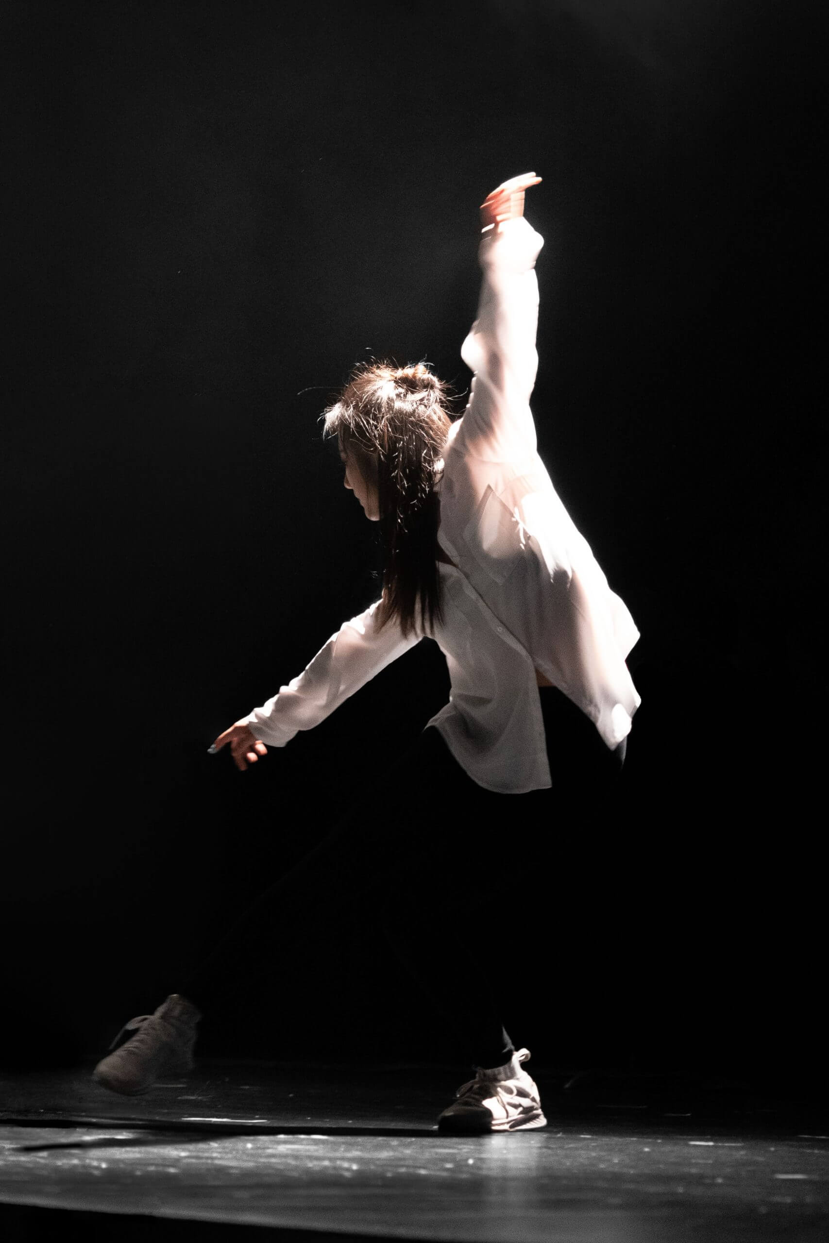 Person dancing on a stage with a black background