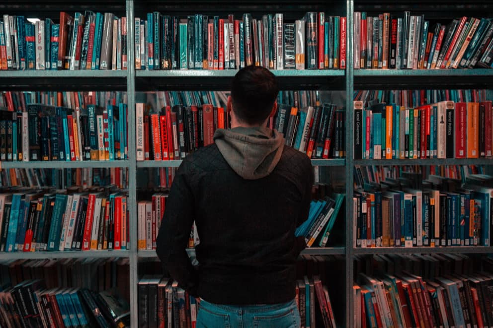 Person facing and looking at a bookshelf